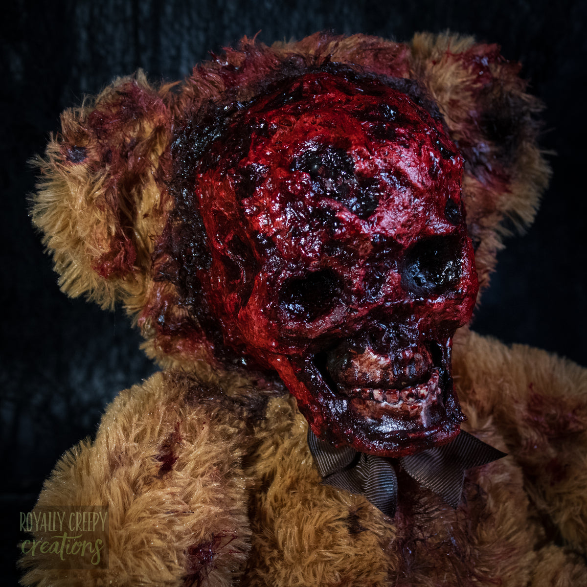 A close-up of a horror teddy bear with an exposed bloody skull for a face.