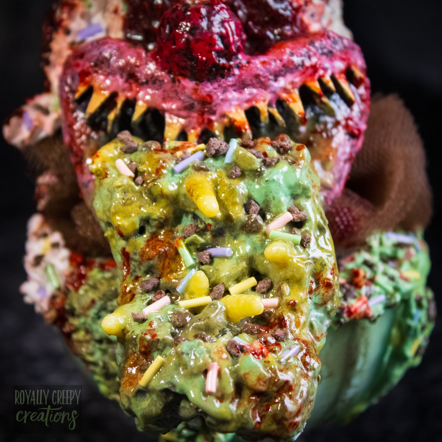 Close-up of a highly detailed sculpture of a horror clown head staged like an ice cream sundae. The clown head is overflowing with whipped cream and ice cream and is sitting in a glass dessert bowl.