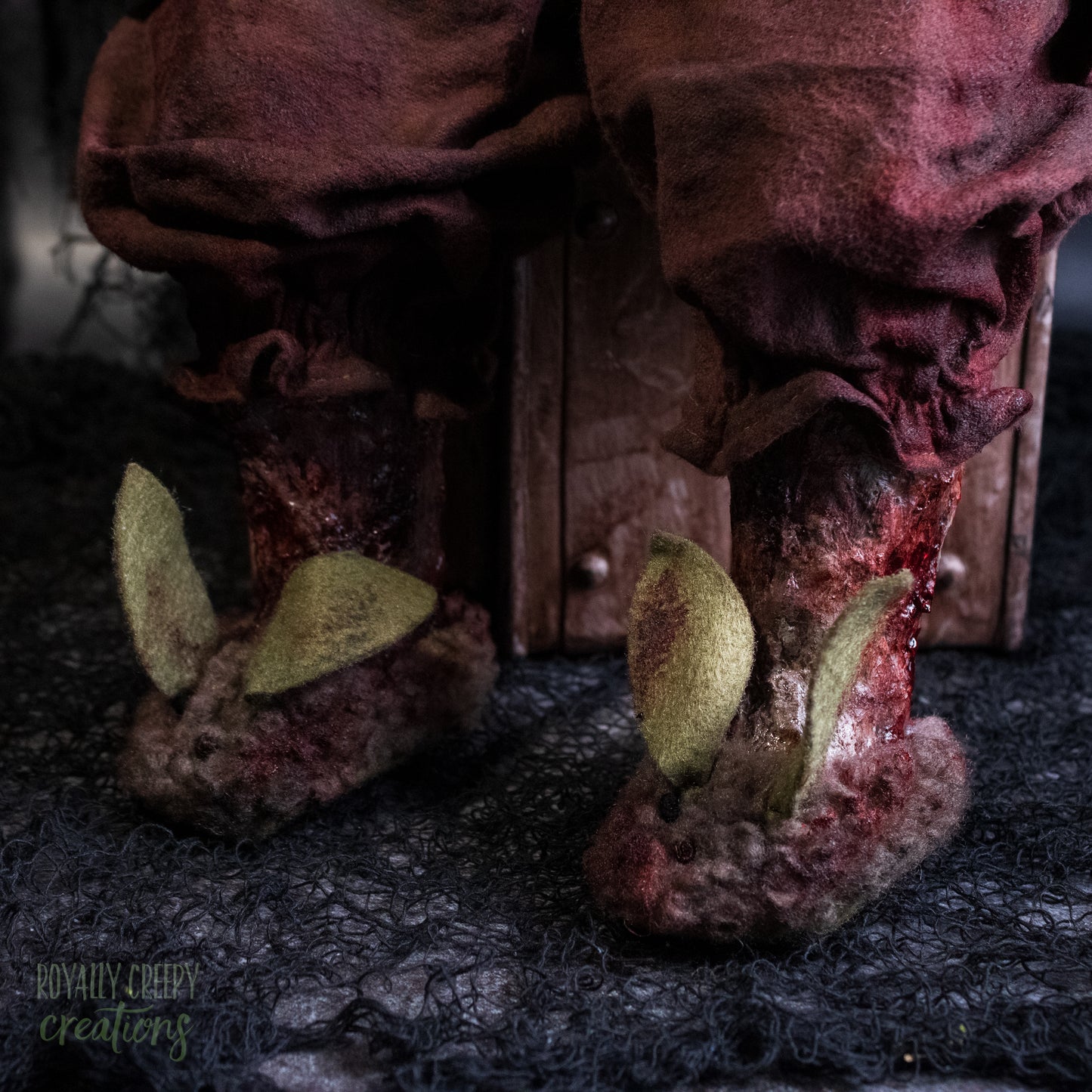 A close up of decayed doll legs wearing tattered bunny slippers.