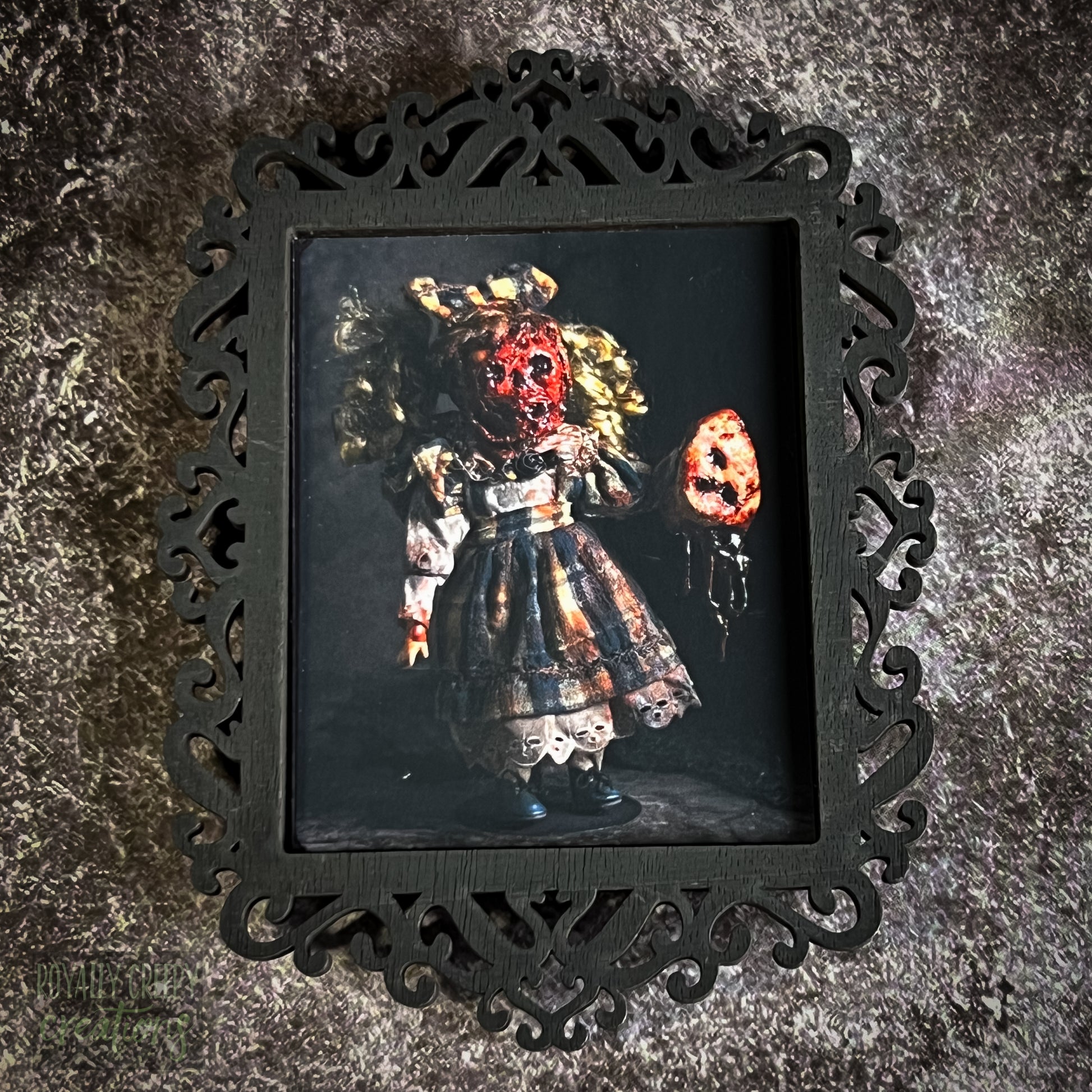 A gothic-style framed art print featuring a dark, eerie photograph of a grotesque doll-like figure.