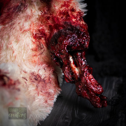 Close-up of creepy teddy bear arm with exposed bone and gore details.