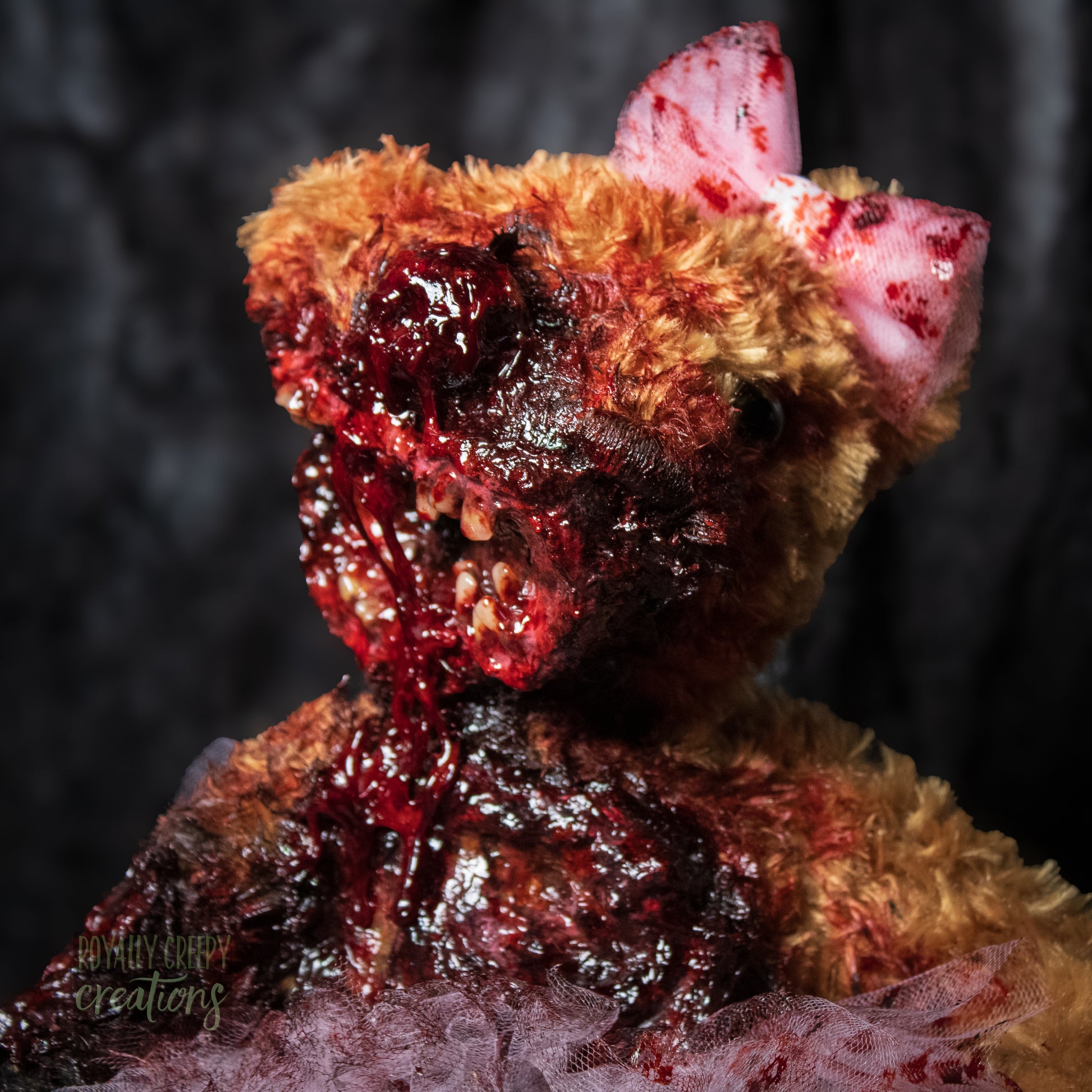 Front view close-up of horror teddy bear with exposed teeth, wearing a tutu & bow.