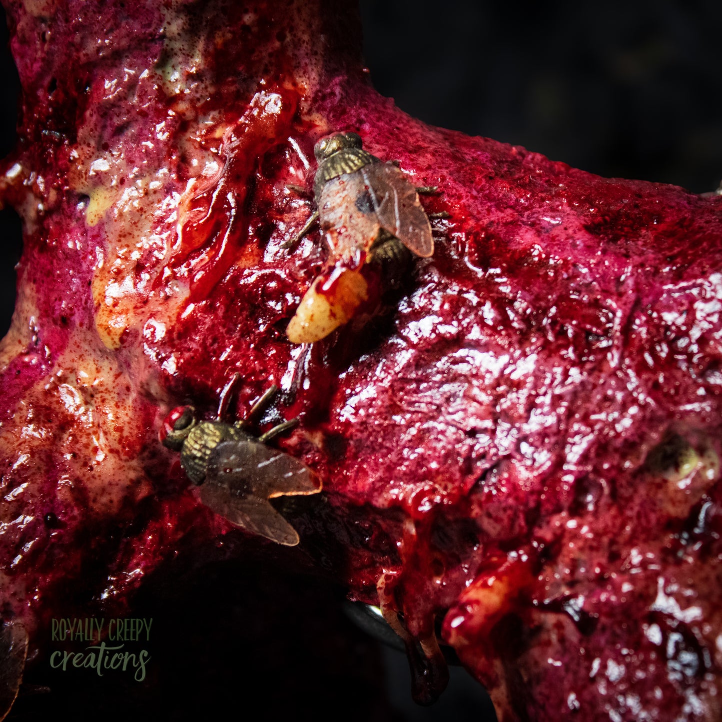 Close-up side of horror version of an infected balloon dog plushie covered in gore, maggots and flies.