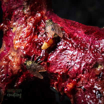 Close-up side of horror version of an infected balloon dog plushie covered in gore, maggots and flies.