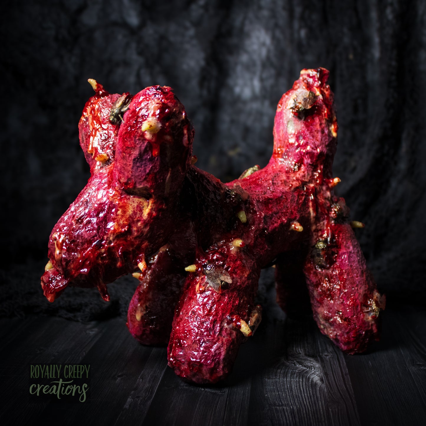 Side of horror version of an infected balloon dog plushie covered in gore, maggots and flies.