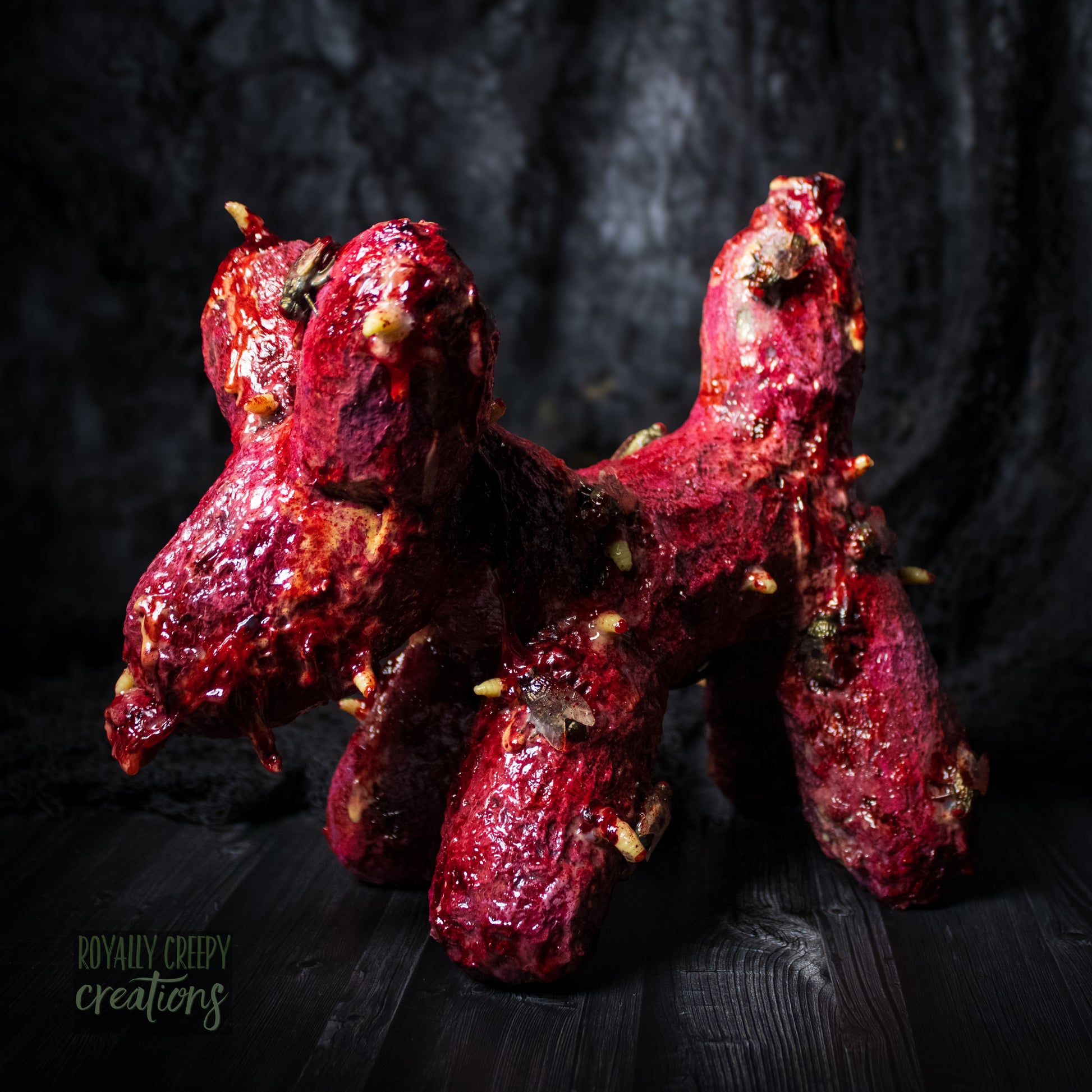Side of horror version of an infected balloon dog plushie covered in gore, maggots and flies.