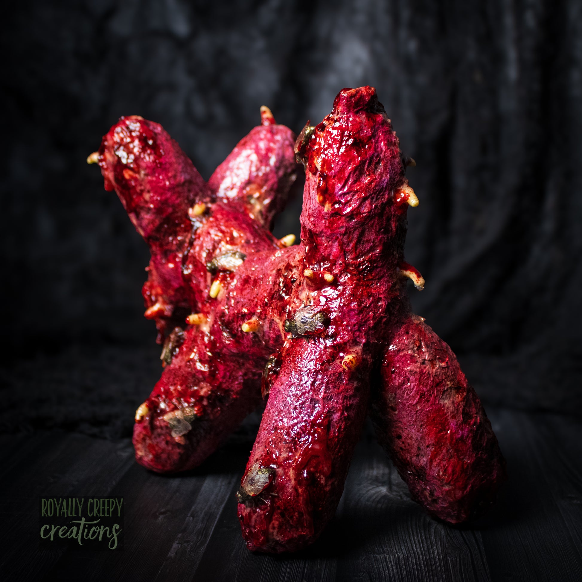 Back side of horror version of balloon dog plushie covered in gore, maggots and flies.