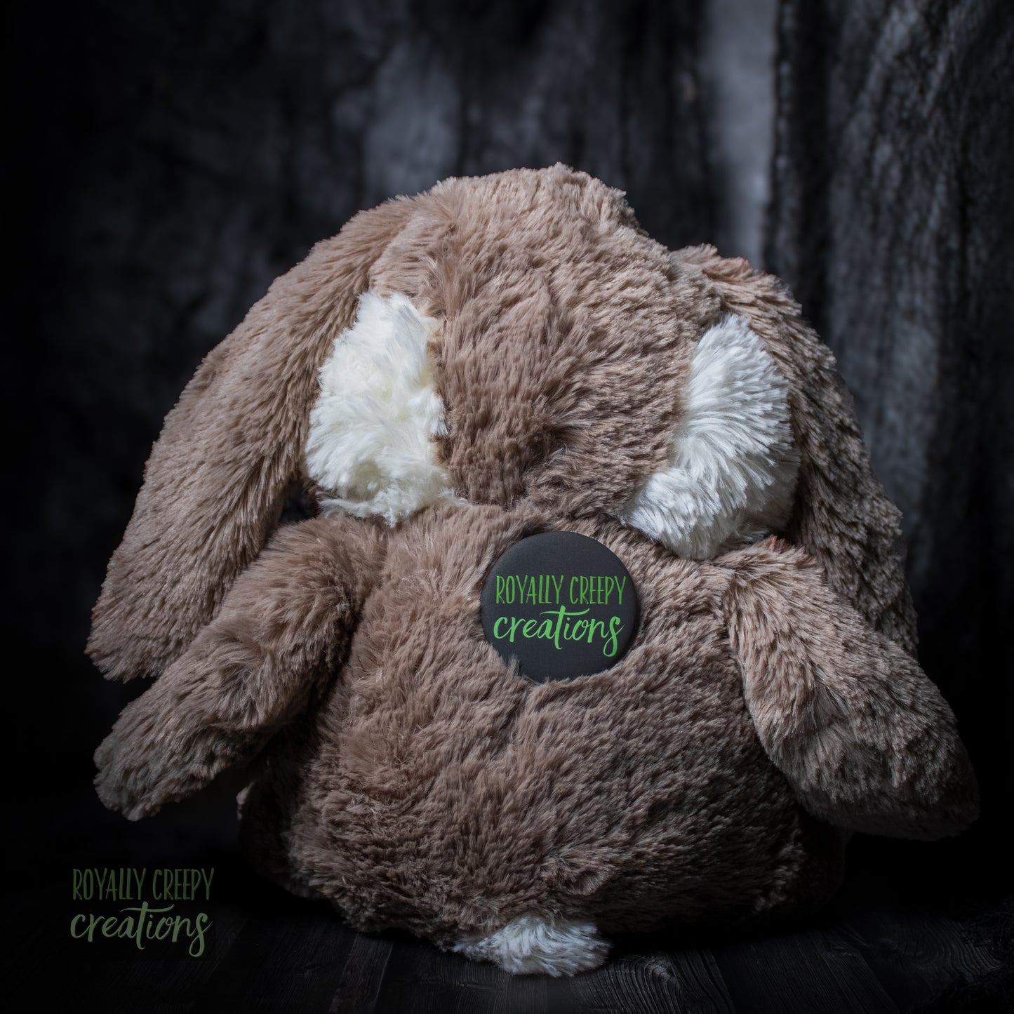 Back of bunny plushie wearing a "Royally Creepy Creations" logo.
