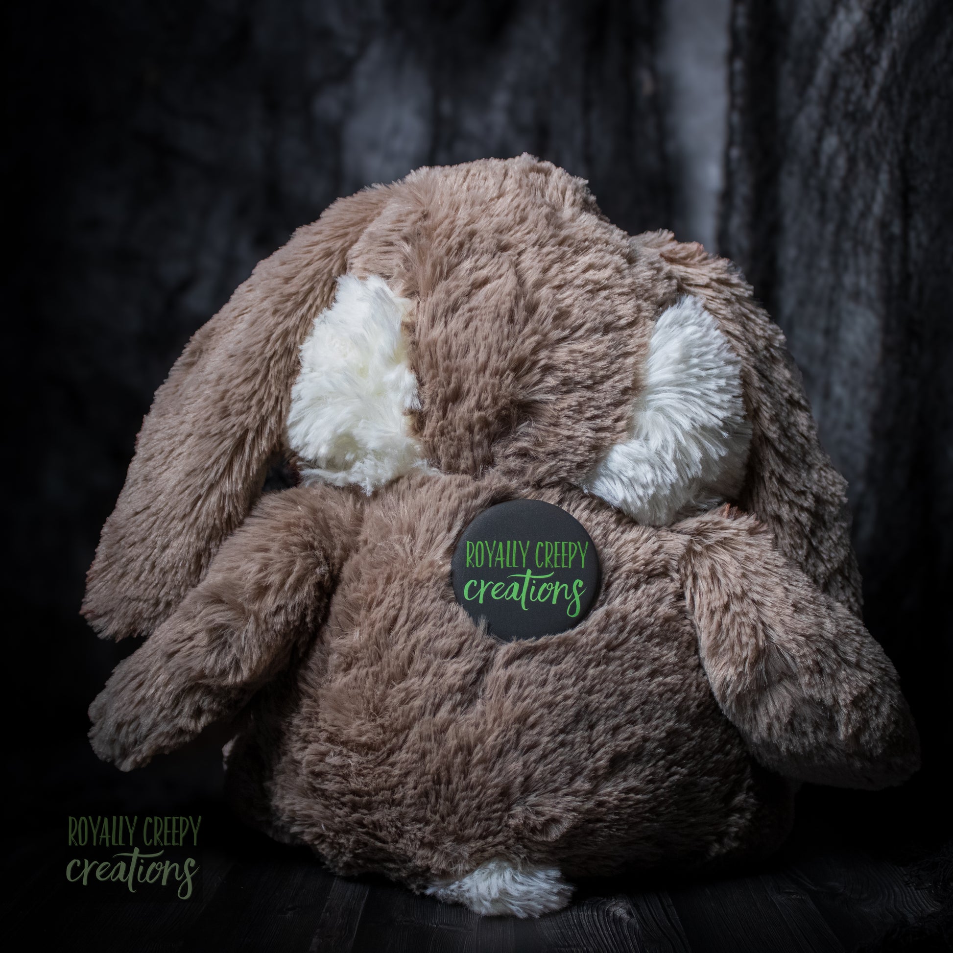 Back of bunny plushie wearing a "Royally Creepy Creations" logo.