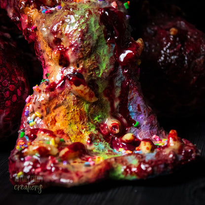 Close-up of bottom of horror vomit rainbow covered with maggots and colorful sprinkles and fake blood.