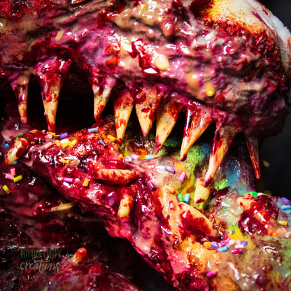 Close-up of top of sharp teeth and horror vomit rainbow covered with maggots and colorful sprinkles and fake blood.