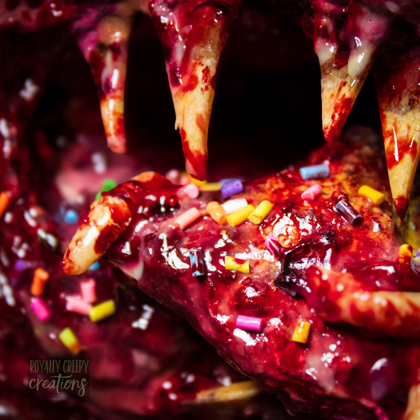 Extreme close-up of sharp teeth and horror vomit rainbow covered with maggots and colorful sprinkles and fake blood.