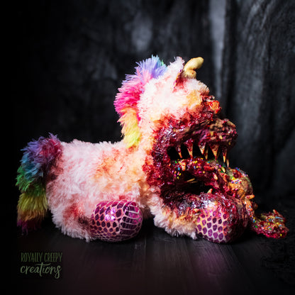 Right side view of horror unicorn plush vomiting a rainbow with a dark background.