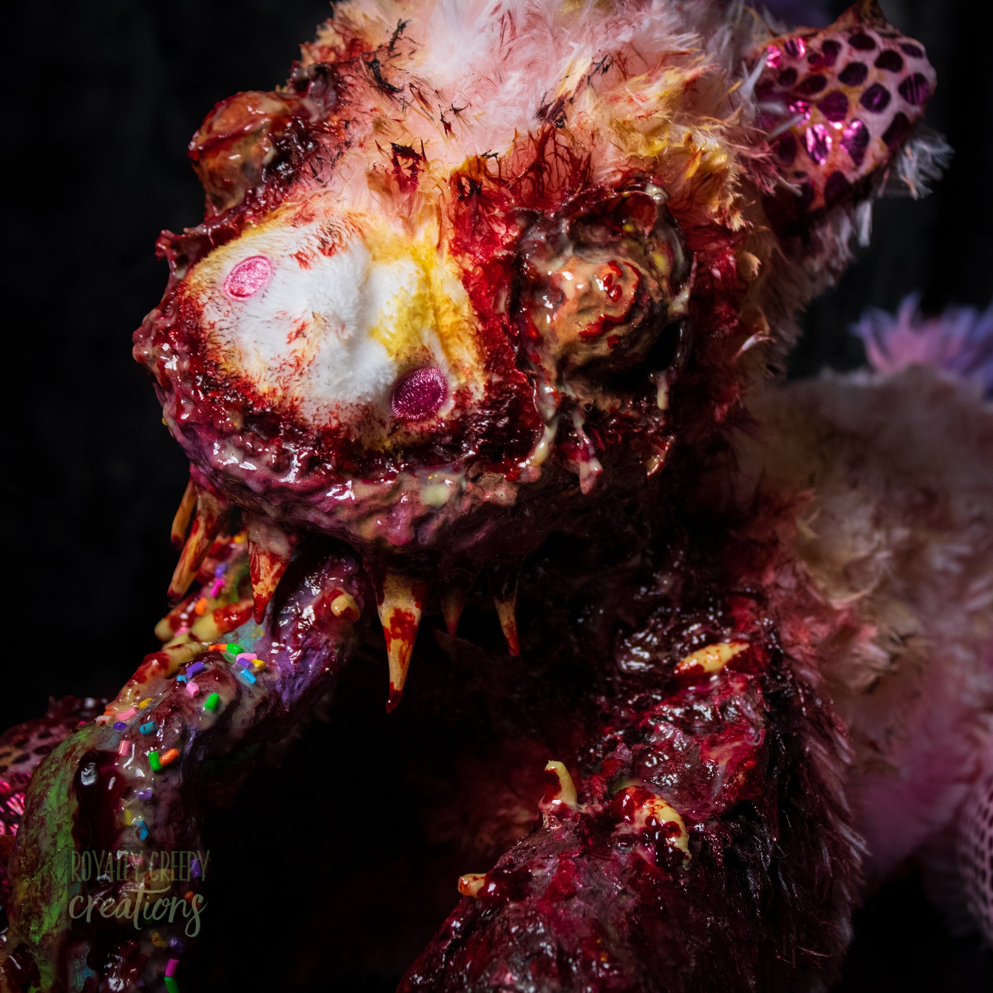 Close-up of unicorn plush mouth vomiting a rainbow with a dark background.