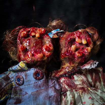 Close-up of conjoined horror doll with a gaping mouth filled with teeth covering both faces.