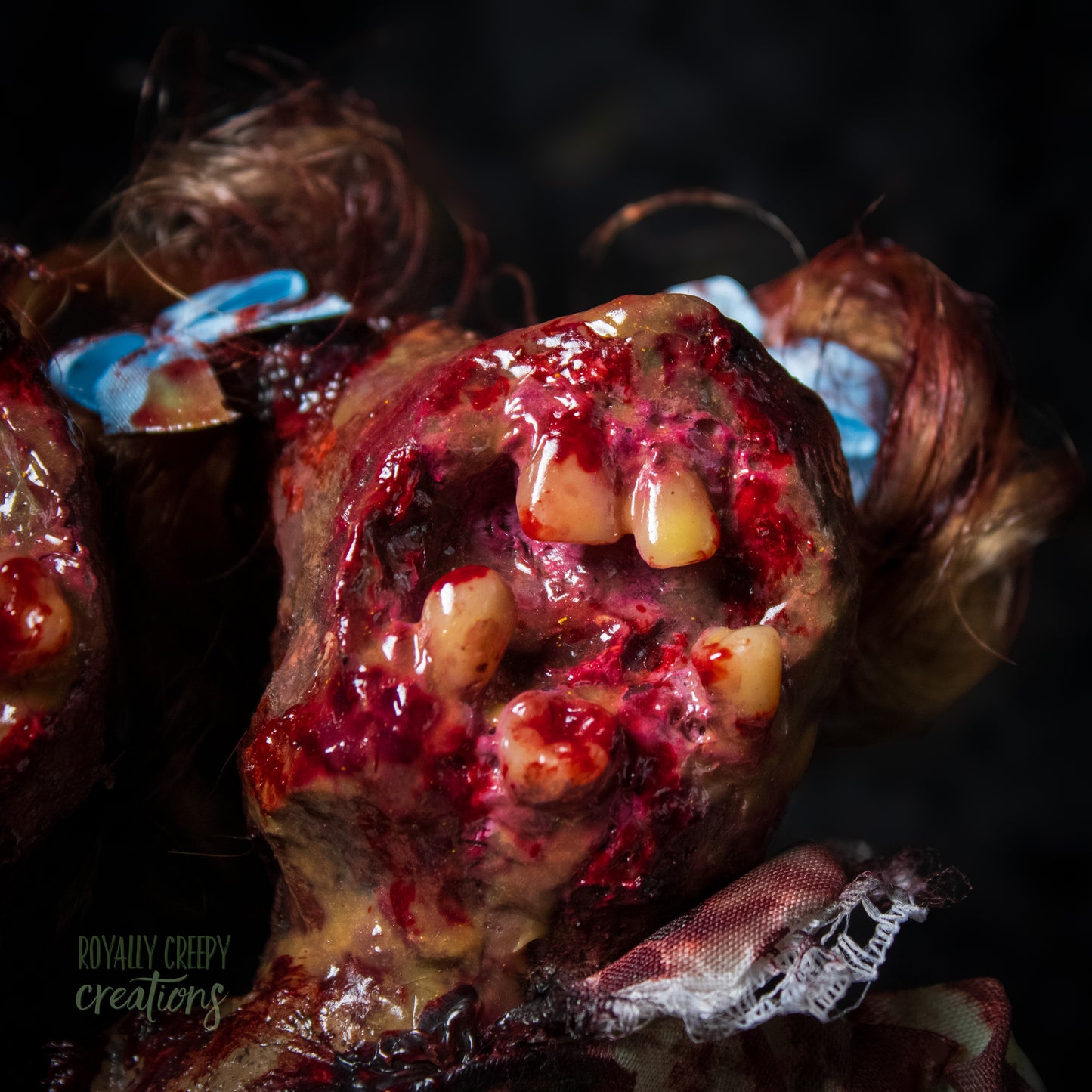 Close-up of female head of conjoined horror doll with a gaping mouth filled with teeth covering entire face.