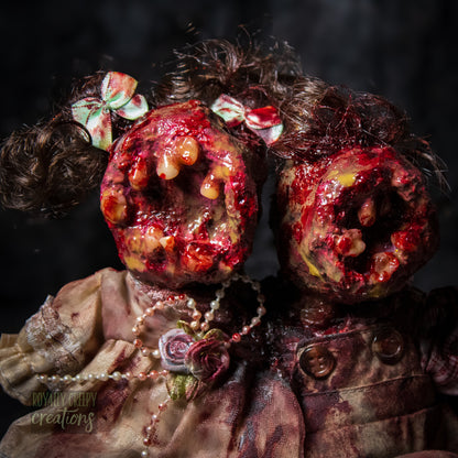 Close-up of conjoined horror doll with a gaping mouth filled with teeth covering both faces.