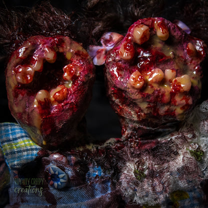 Close-up of conjoined horror doll with a gaping mouth filled with teeth covering both faces.