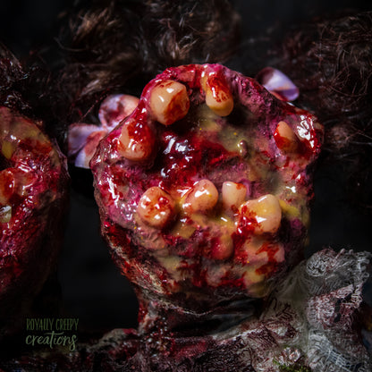 Close-up of female head of conjoined horror doll with a gaping mouth filled with teeth covering entire face.