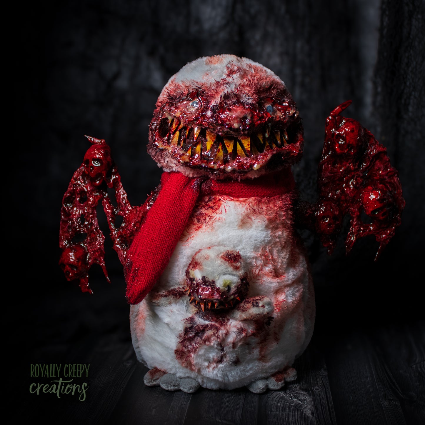 Gory winged bird creature-like figure with fake blood and sharp teeth and a little bird creature sticking out of it's stomach pouch.