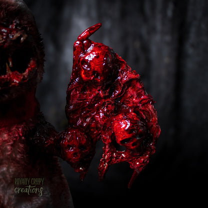 Close-up of a bloody, textured left wing embedded with skulls. 