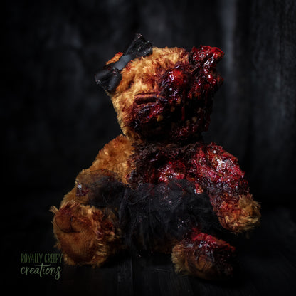 A horror-themed plush teddy bear with a grotesque, gory zombie-like face, bared teeth, and exposed flesh details, wearing a black tutu and black bow, set against a dark, moody background.