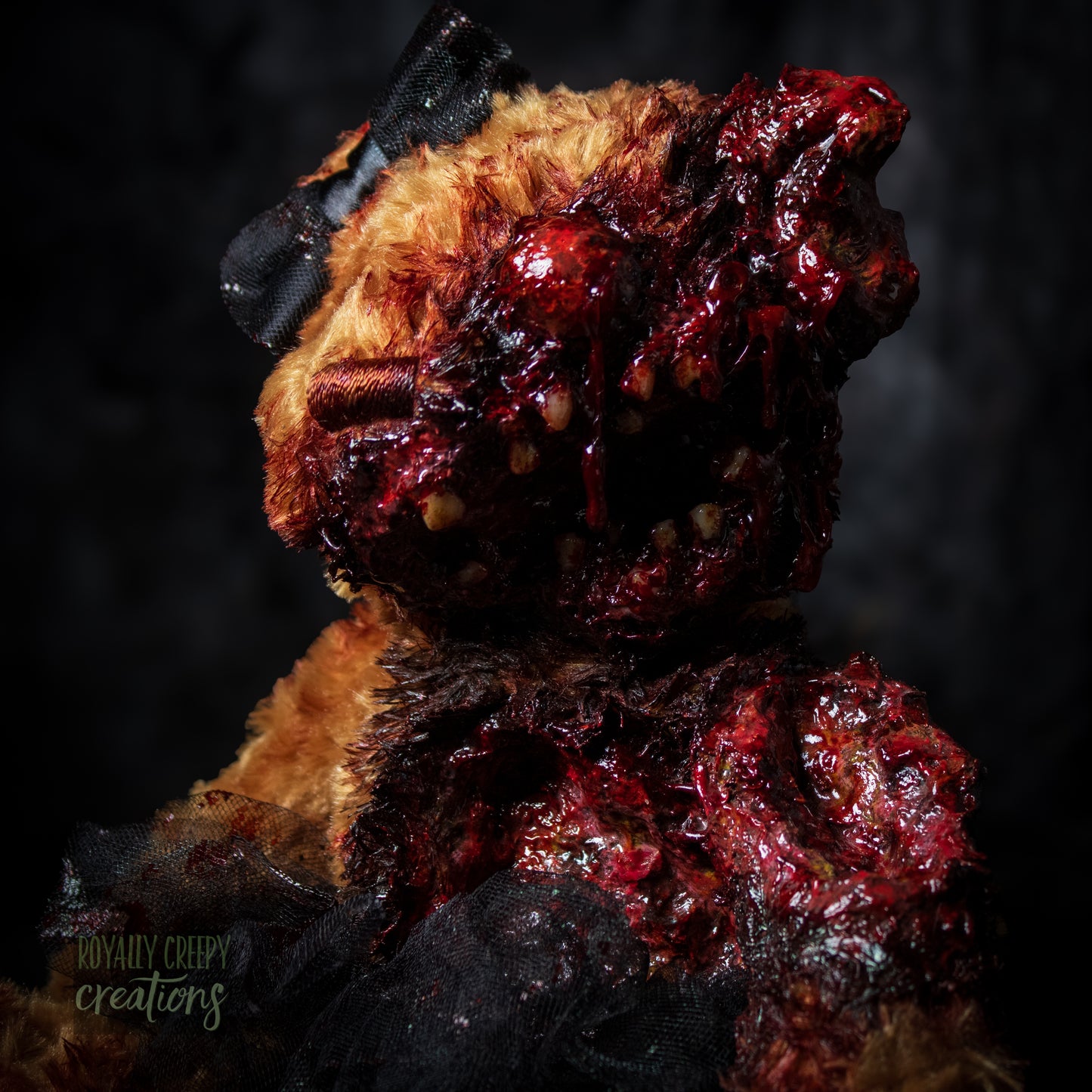 A horror-themed plush teddy bear with a grotesque, gory zombie-like face, bared teeth, and exposed flesh details, wearing a black tutu and black bow, set against a dark, moody background.
