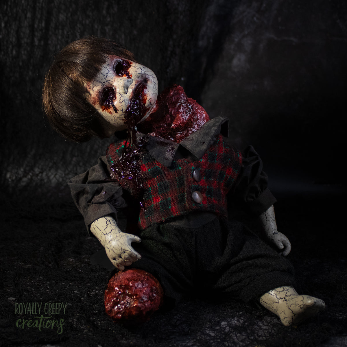A creepy horror doll with a grotesque bloody wound on the neck, posed on a dark textured background with a severed grotesque leg.