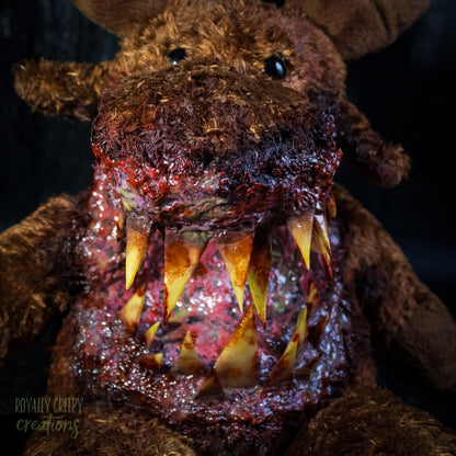 A close-up of a creepy moose plush toy with a horror zombie-like mouth, showing exposed flesh and sharp yellowed teeth, set against a dark textured background.