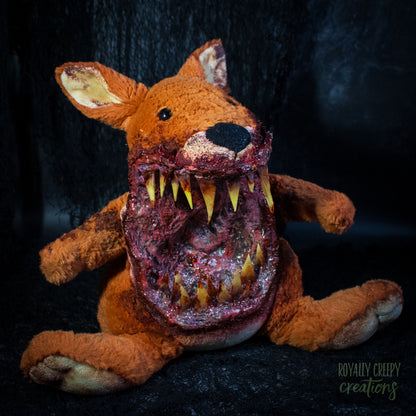 A horror-themed plush kangaroo toy with a grotesque, bloody open mouth showing sharp yellow teeth, posed against a dark textured background. A 'Royally Creepy Creations' watermark is visible in the bottom corner.