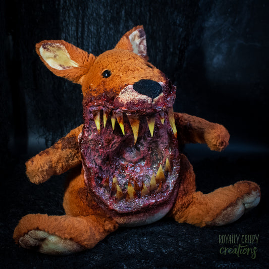 A horror-themed plush kangaroo toy with a grotesque, bloody open mouth showing sharp yellow teeth, posed against a dark textured background. A 'Royally Creepy Creations' watermark is visible in the bottom corner.