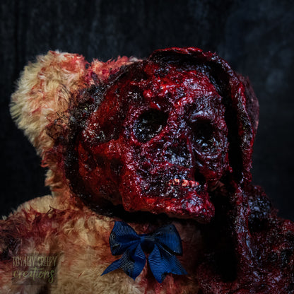 A close up of a horror-themed plush teddy bear with an exposed bloody skull for a face, and a dark blue bow tie, set against a dark textured background.