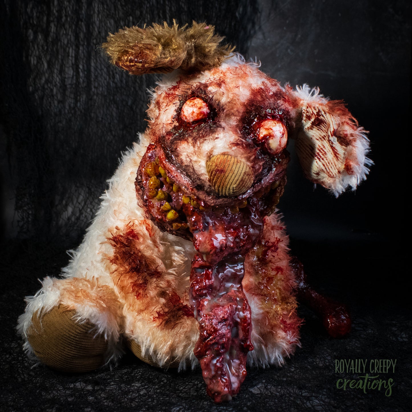 A horror-themed zombie dog plush toy with tattered fur, bloodshot red eyes, a bloody gaping mouth, and a protruding tongue, posed against a dark textured background