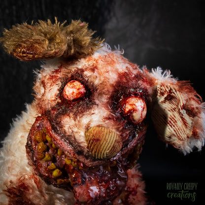 A close-up of a  horror-themed zombie dog plush toy with tattered fur, bloodshot red eyes, a bloody gaping mouth.