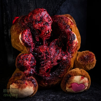 A horror-themed plush teddy bear that is split down the middle and a gory bloody skeleton is emerging from it's opening.