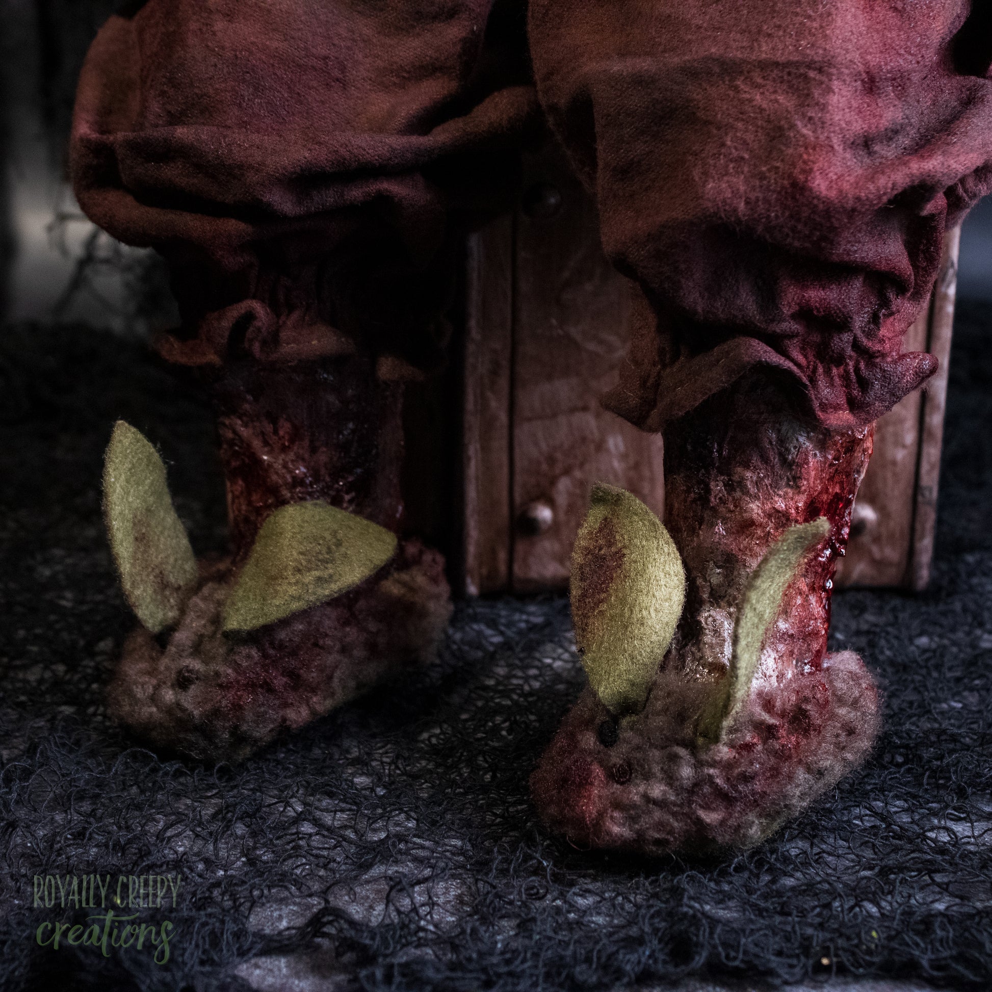 A close up of decayed doll legs wearing tattered bunny slippers.