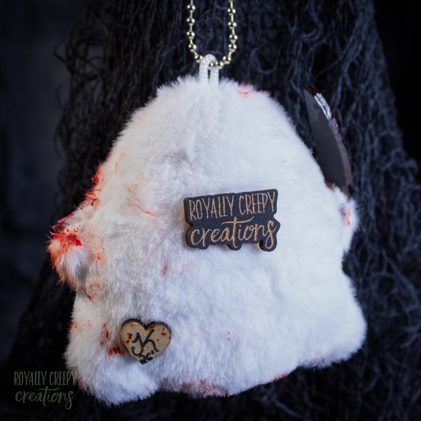 The back of a grotesque plush ghost keychain holding a fake knife.