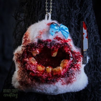 A grotesque plush ghost keychain holding a fake bloody knife.