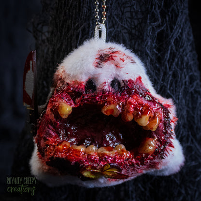 A grotesque plush ghost keychain holding a fake bloody knife.