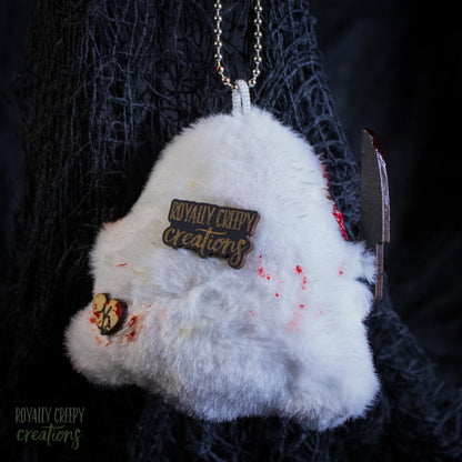 The back of a grotesque plush ghost keychain holding a fake knife.