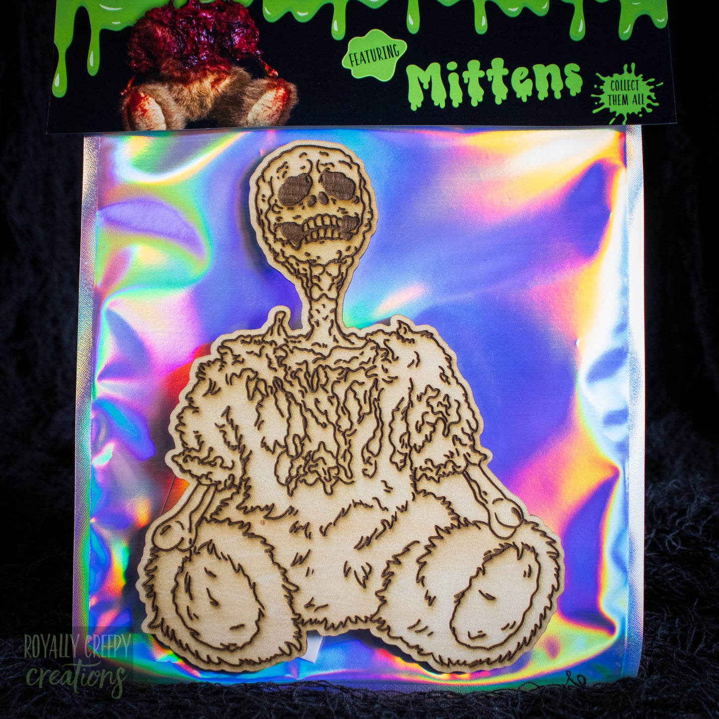A packaged craft item showing a laser-cut wooden skeleton bearon an iridescent holographic backing card.