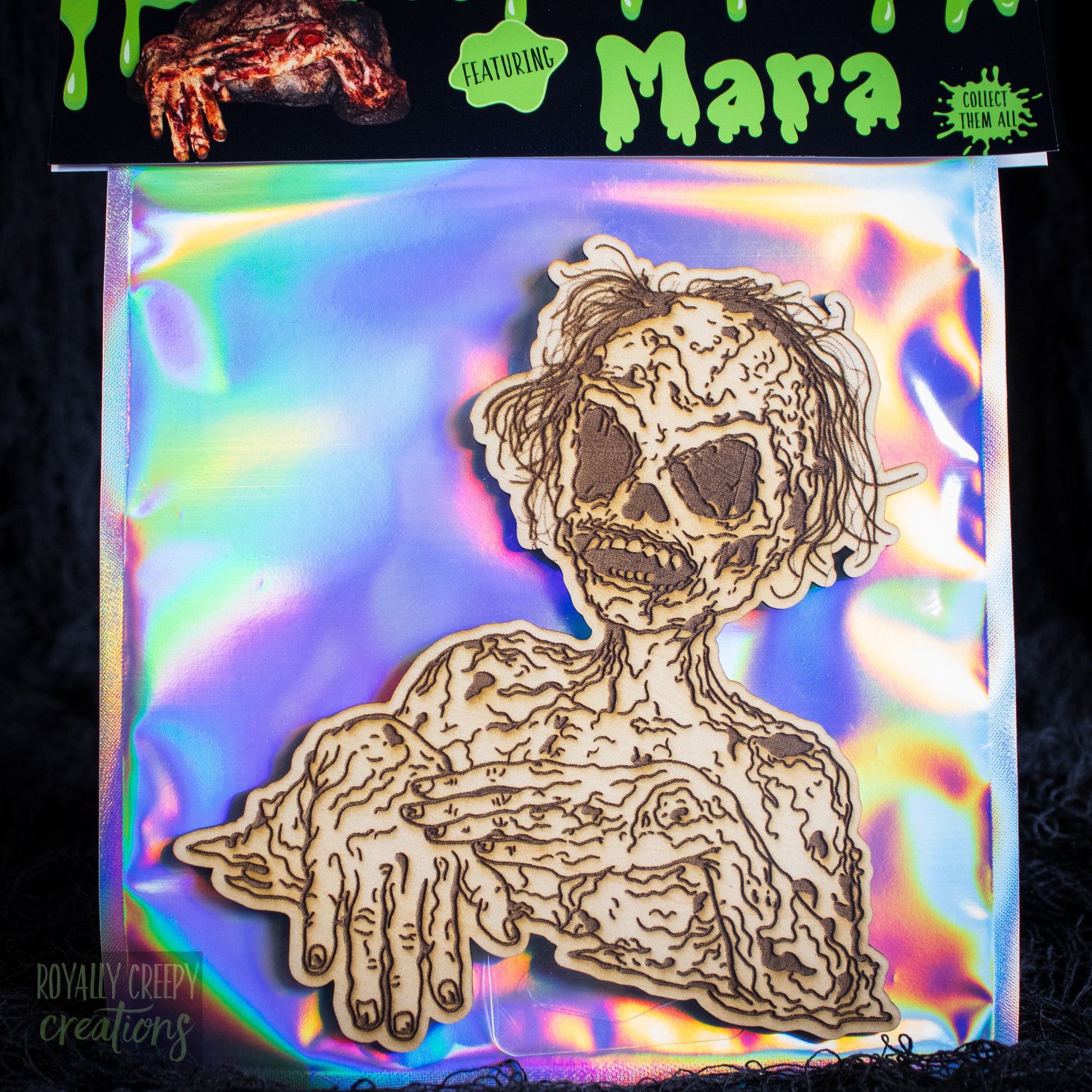 A packaged craft item showing a laser-cut wooden skeleton/creeper figure on an iridescent backing card. The top header reads 'Mara'.