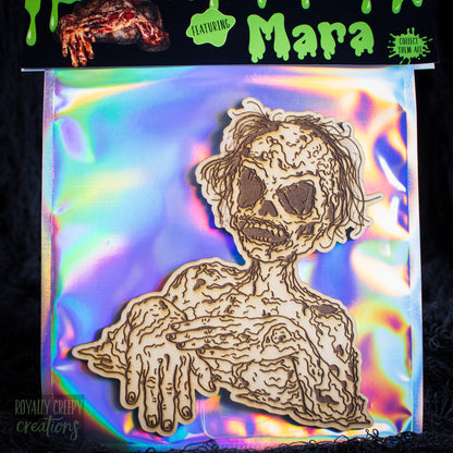 A packaged craft item showing a laser-cut wooden skeleton/creeper figure on an iridescent backing card. The top header reads 'Mara'.