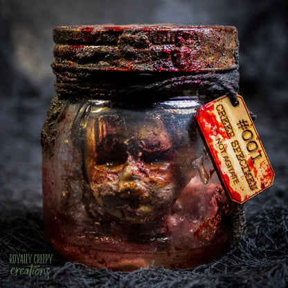 A creepy specimen prop of a severed doll head inside a dirty, rusted glass jar with a dark lid and rope, set against a dark textured background.