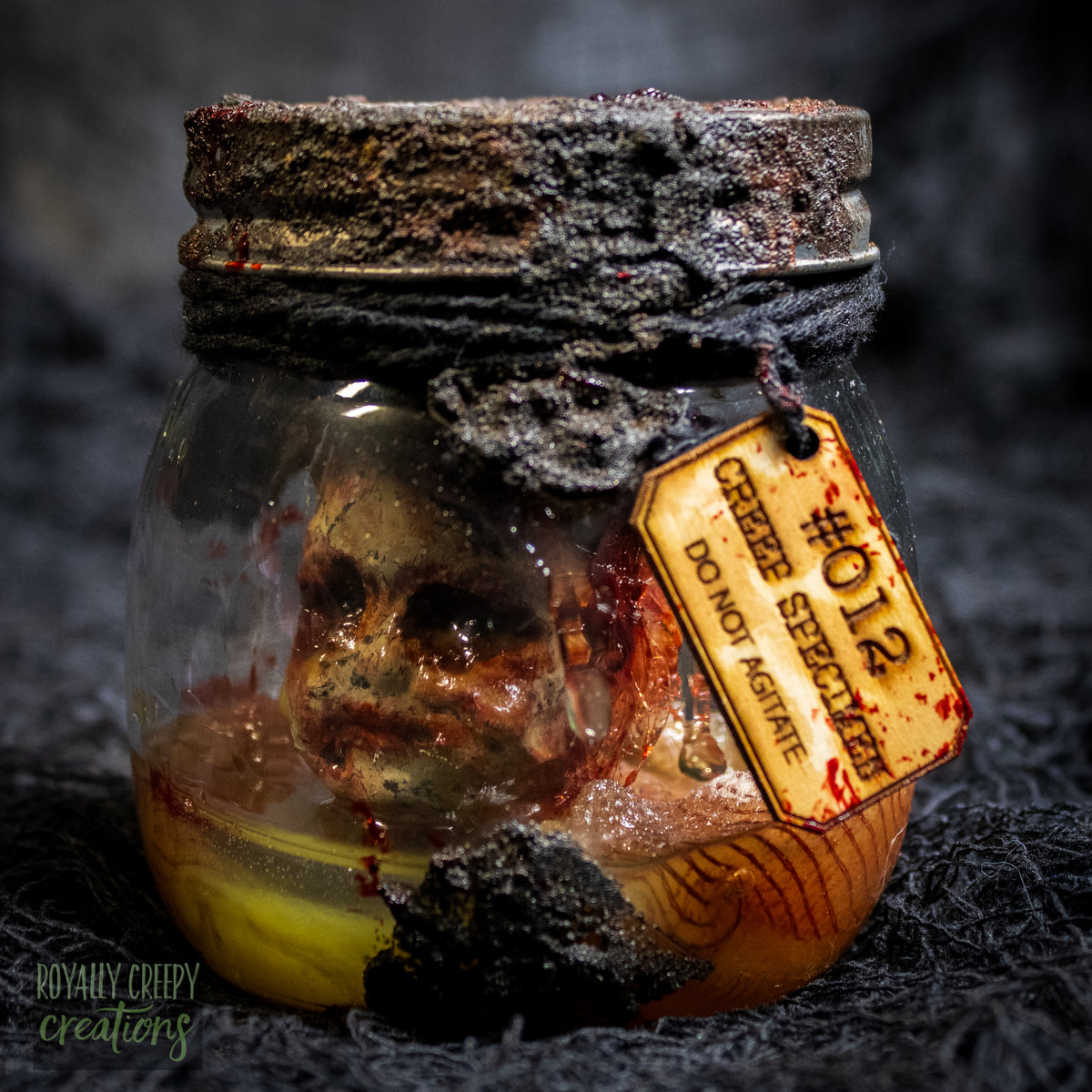 A creepy specimen prop of a severed doll head inside a dirty, rusted glass jar with a dark lid and rope, set against a dark textured background.