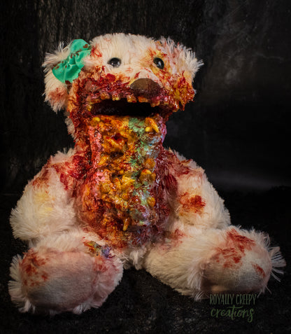A horror-themed plush teddy bear with a pastel colored vomit & maggots spewing from it's mouth 