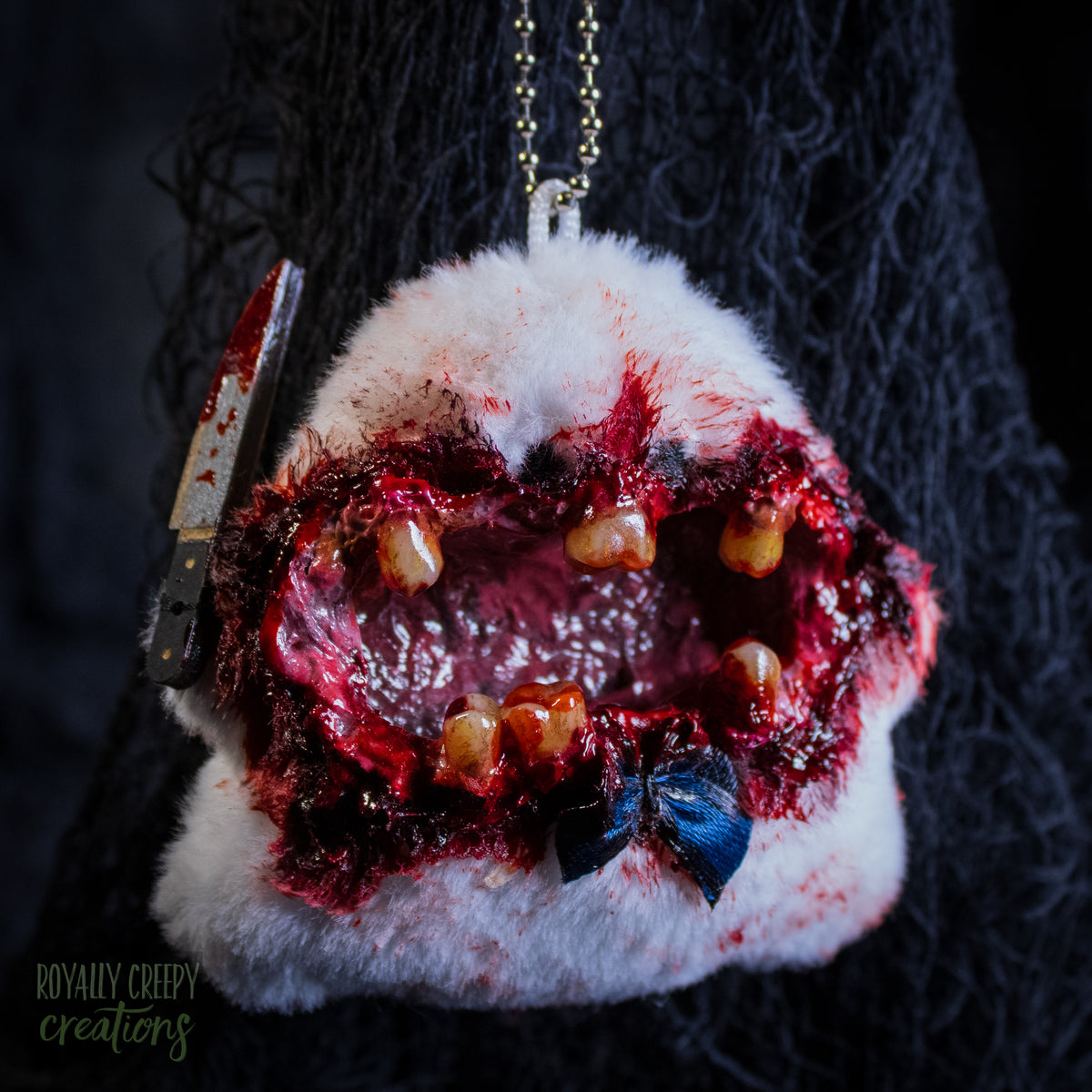 A grotesque plush ghost keychain holding a fake bloody knife.